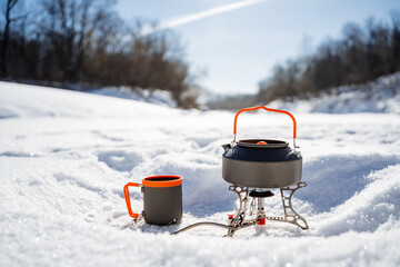 Camping equipment utensils stand on the snow while hiking against the background of the winter...