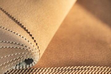 A set of pieces of genuine animal leather samples in brown and beige shades and colors with a blurred background close-up with copy space.