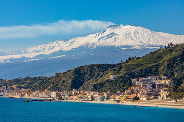 Panoramic view of Taormina shore at Ionian sea with Giardini Naxos and Villagonia towns and Mount Etna volcano in Messina region of Sicily in Italy