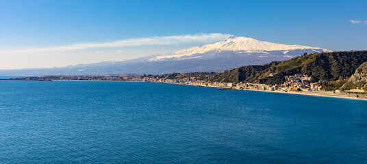 Panoramic view of Taormina shore at Ionian sea with Giardini Naxos and Villagonia towns and Mount Etna volcano in Messina region of Sicily in Italy