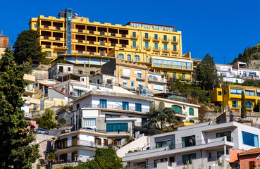 Panoramic view of Taormina houses and residences on slope of Monte Tauro rock over Ionian Sea shore in Messina region of Sicily in Italy - 747807285