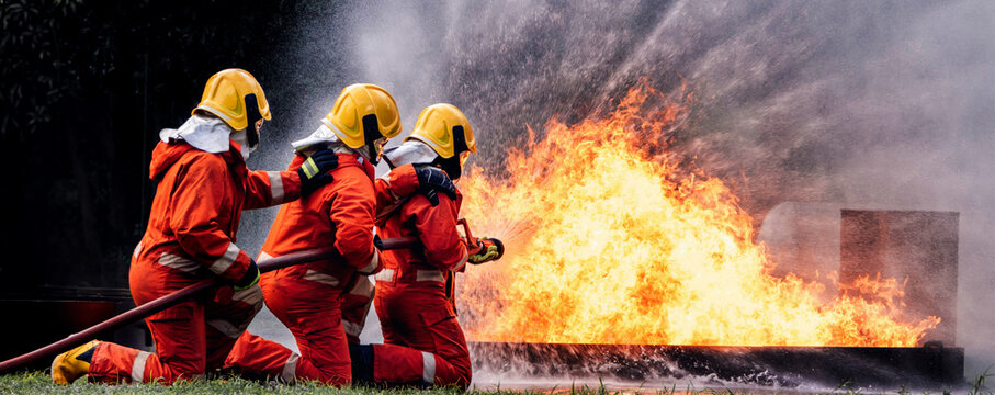 Firefighter Concept. Several firefighters go offensive for a fire attack. Fireman using water and extinguisher to fighting with fire flame.