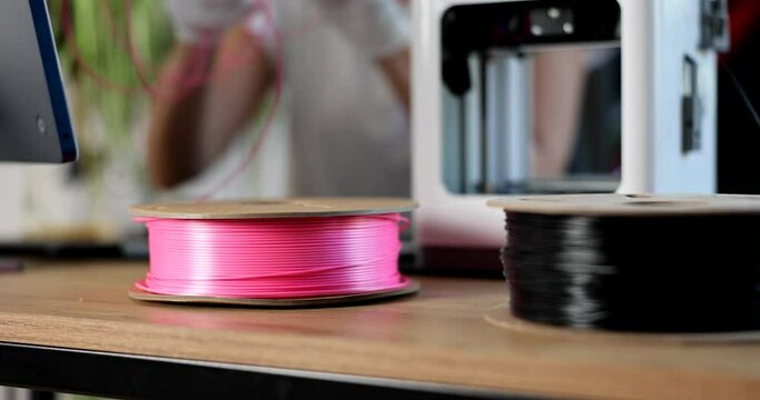 Engineer in gloves holds pink plastic for 3d printers. Choice of materials for 3D printing