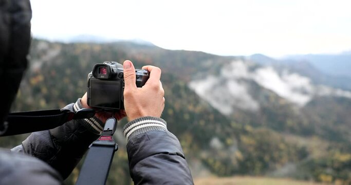 Travel photographer takes pictures with telephoto lens in mountains. Beautiful landscape of mountains in Georgia