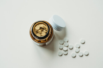 Close-up of white pills and bottle with a lid on table