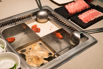 Close up of the half soup base steamboat with Mala soup and raw pork slices,Fresh vegetables...
