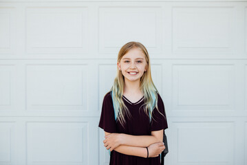 Portrait of preteen girl smiling in front of clean background.