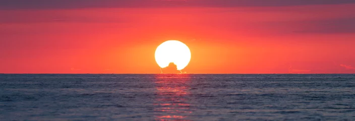 Fotobehang The red sun sets in the sea © Daniel