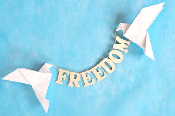 Concept of freedom. White dove origami carrying word heaven in sky blue background.	