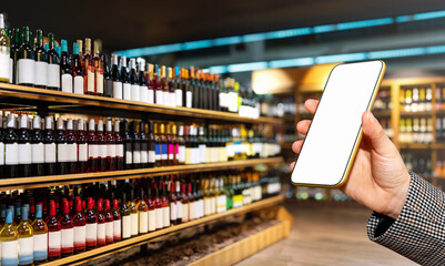 Female hand showing empty screen of her smart phone in front of liquor store with wine bottles on...