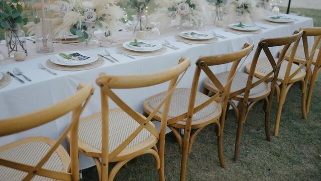 Luxury decoration reception dinner set up Romantic decoration wedding setup Festive fine setting table row chair flDinner table setup sunset background. Close up decoration flowers candles Boho style.