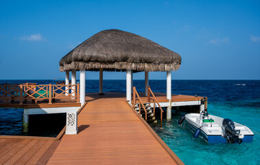 A white boat with a black engine tied up at a wooden pier.