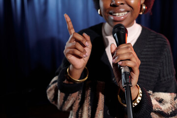 Microphone held by young African American comedian of stand up show pronouncing monologue while...