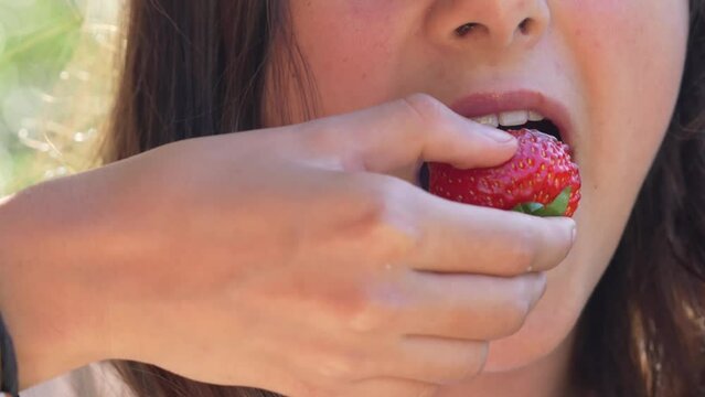 A young girl eating a strawberry, slow motion