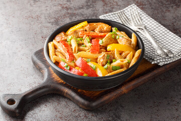 Jamaican Style Rasta Pasta Penne with Grilled Chicken and Bell Peppers closeup on the bowl on the wooden board. Horizontal
