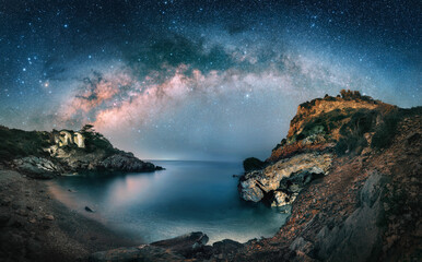 Amazing starry night sky with the majestic Milky Way over a scenic coast at a bay. A majestic...