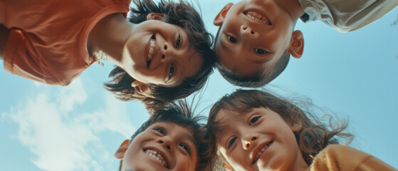 Four joyful children bonding in a huddle, their faces glowing under a clear blue sky.