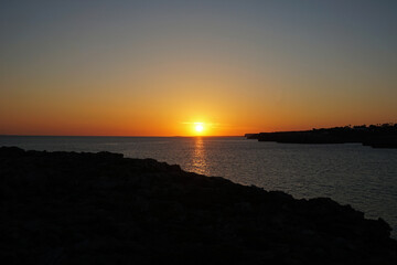 Natural landscape of Playa de Cavalleria (Mercadal) in Minorca beach with sunset sky and rocky seashore- Menorca, Spain
