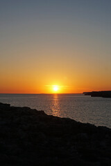 Obraz premium Natural landscape of Playa de Cavalleria (Mercadal) in Minorca beach with sunset sky and rocky seashore- Menorca, Spain