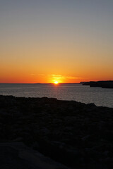 Natural landscape of Playa de Cavalleria (Mercadal) in Minorca beach with sunset sky and rocky seashore- Menorca, Spain