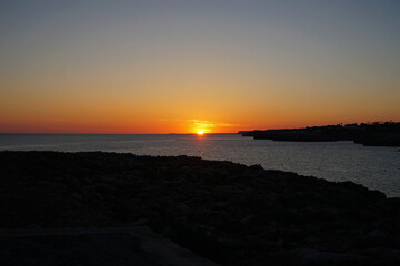 Natural landscape of Playa de Cavalleria (Mercadal) in Minorca beach with sunset sky and rocky seashore- Menorca, Spain
