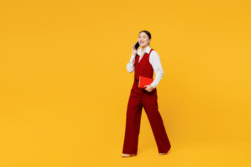 Full body side view young lawyer employee business woman of Asian ethnicity wearing red vest shirt...