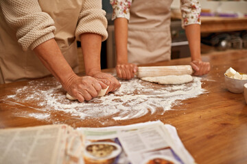 Dough, recipe and hands of people on table, baking in kitchen and closeup on process in bakery. Person, prepare and press bread with flour, meal prep and working with information or guide from book - obrazy, fototapety, plakaty