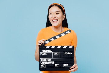 Young woman of Asian ethnicity wear orange t-shirt casual clothes hold in hand classic black film...