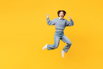 Fototapeta na wymiar Full body young excited fun woman she wears grey knitted sweater shirt casual clothes jump high do winner gesture looking camera isolated on plain yellow background studio portrait. Lifestyle concept.