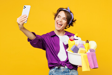 Young woman wear purple shirt hold basin with detergent bottles do housework tidy up do selfie shot...