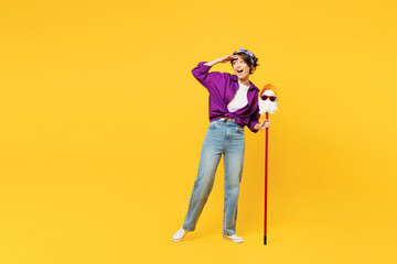 Full body young woman wear purple shirt casual clothes do housework tidy up hold in hand mop in hat and glasses look far away distance isolated on plain yellow background studio. Housekeeping concept. - obrazy, fototapety, plakaty