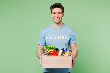 Young man wear blue t-shirt white title volunteer give box with vegetarian vegan food vegetables...