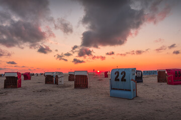 Wicker beach chairs on the sand beach of Neuharlingersiel at sunset, North Sea, East Frisia, Lower...