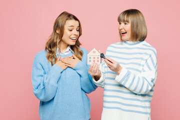 Full body shocked fun elder parent mom with young adult daughter two women together wear blue casual clothes hold keys house mockup isolated on plain pastel light pink background. Family day concept.