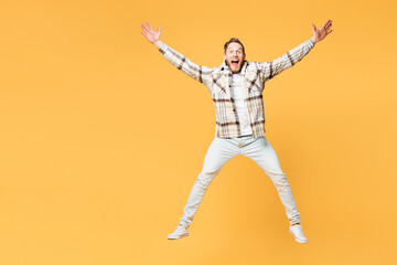 Fototapeta na wymiar Full body overjoyed exultant young Caucasian man wear brown shirt casual clothes jump high with outstretched hands legs isolated on plain yellow orange background studio portrait. Lifestyle concept.