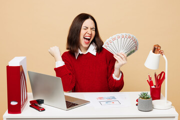 Young winner employee business woman in red sweater shirt sit work at office desk with pc laptop...
