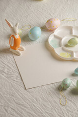 Easter, spring, copy space, Easter decorative eggs in pastel colors and narcissus on the table, white background, watercolor paints and palette, 