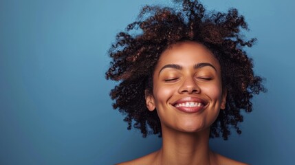Joyful african american woman smiling with eyes closed against blue background