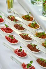 Appetizer for the banquet - different types of salmon, beef and tuna tartare on the table