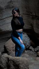 Mujer en sitio con paredes de roca y picón en la isla de Gran canaria con ropa normal de mujer gafas de sol posando natural
