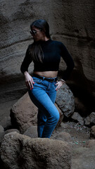 Mujer en sitio con paredes de roca y picón en la isla de Gran canaria con ropa normal de mujer gafas de sol posando natural