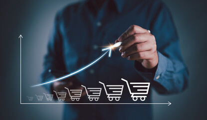 Businessman drawing increasing trend graph of sale volume with bigger shopping trolley cart for online sale business growth concept.. - obrazy, fototapety, plakaty