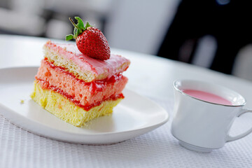 a piece of sponge cake with a cup of strawberry milk on the table