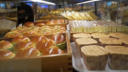 Assorted pastry and bread arranged on tray selling at bakery shop. People can seen picking their favorite bread and put on the food tray.