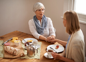 Senior mom, daughter and home with conversation in table for bonding, support and visit. Holding hands, family and meal with tea, food and chat on breakfast together with care, smile and love