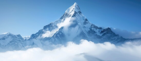 A snow-covered mountain peak towering over the clouds below. The foggy foreground adds to the dramatic scene of natures power and beauty.