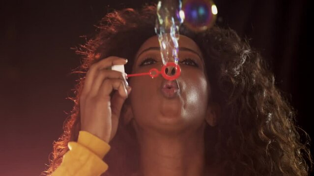 Afro American woman blowing soap bubbles