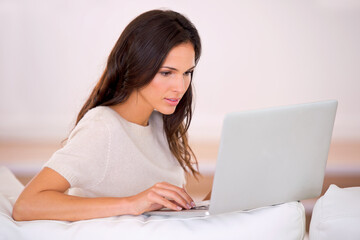 Woman, laptop and typing on sofa for remote work from home with thinking, idea or writing article. Person, girl or writer on computer in lounge with research for story, blog or report at media agency