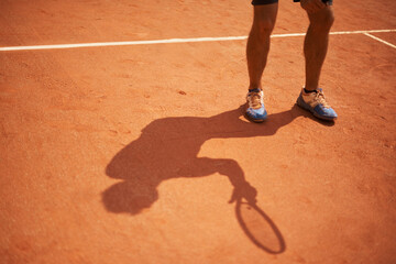 Tennis, court and shoes of athlete outdoor at start of exercise of workout in competition. Person, shadow and sneakers on feet of player training on clay pitch in game of sport with fitness or action