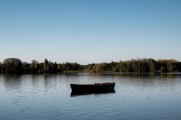 Boat on the lake with autumn forest in the background and blue sky